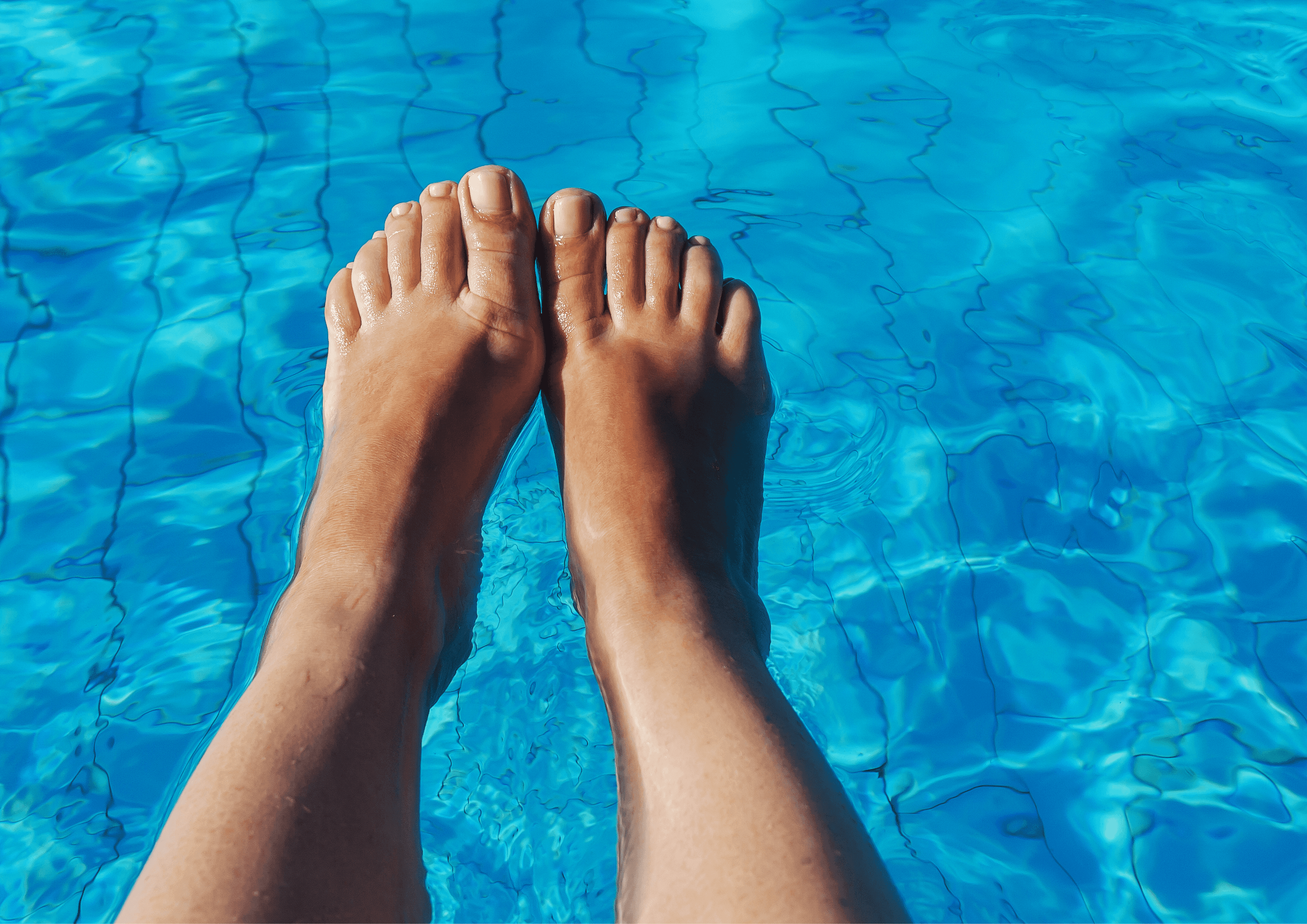 Jemand hält die Füsse über ein Schwimmbecken und fotografiert aus eigener Perspektive.