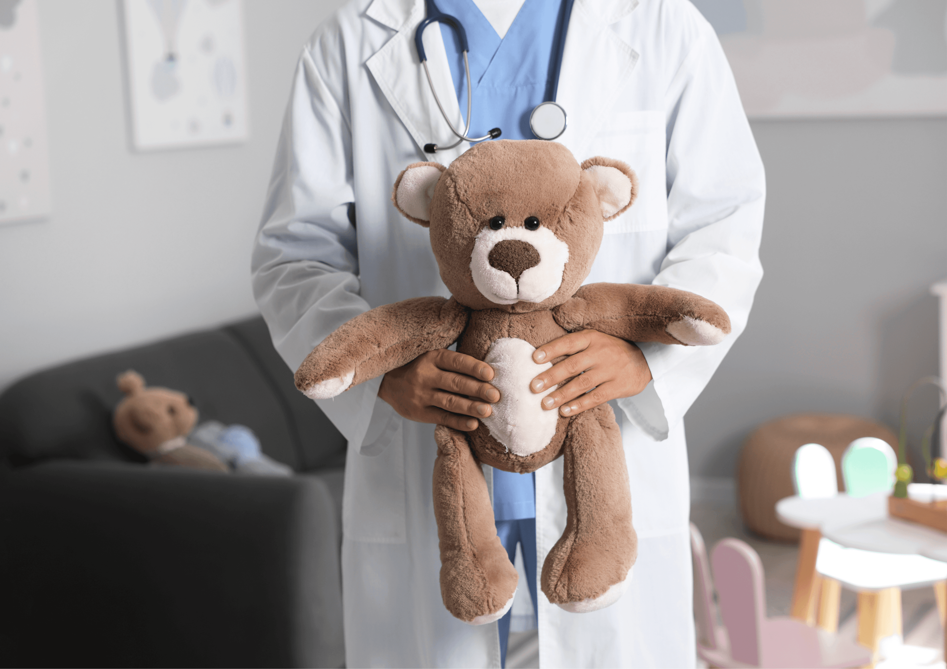 Mensch min Arzt-Kleidung, den Kopf sieht man nicht, hält einen Teddybären in den Händen.